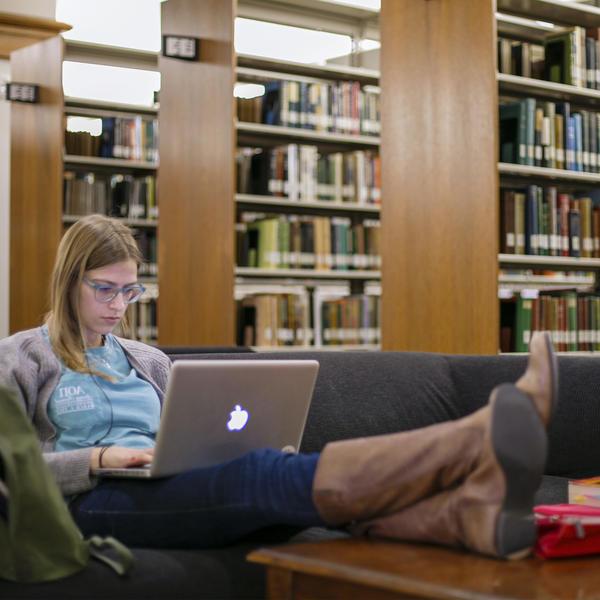 一个学生在图书馆用笔记本电脑学习.